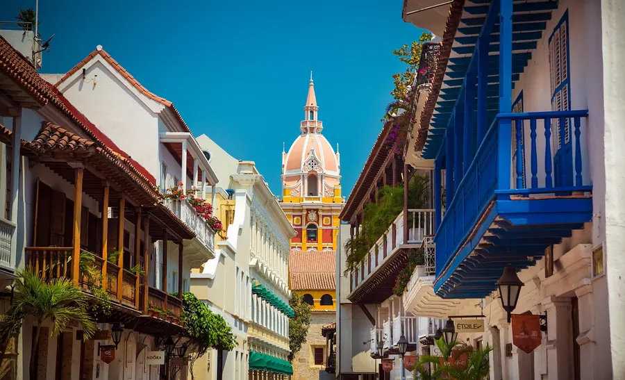 Calle colonial con balcones de colores y una catedral al fondo